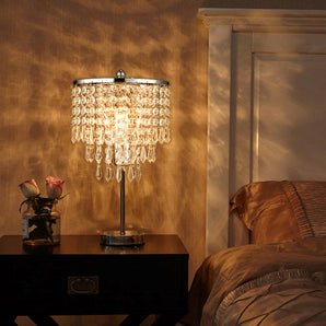 Small crystal table lamp with round base and dangling chandelier-style prisms