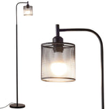 Close-up of black floor lamp with iron mesh shade and exposed bulb glow