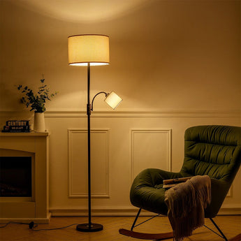 Black standing lamp with beige drum shade and curved arm spotlight head