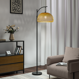 Woven rattan dome shade on black floor lamp with arched metal frame