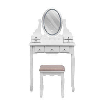 White makeup vanity desk with oval mirror and drawers, plus cushioned stool