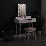 White vanity table with illuminated mirror, two drawers, and upholstered stool