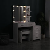 Gray vanity table with large lighted mirror and built-in shelves, plus cushioned stool