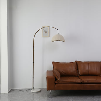 Front view of fabric floor lamp with cream dome shade and arched bronze frame