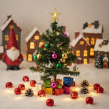 Mini artificial Christmas tree with gold star, red and green baubles, lights, gift boxes