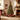 Artificial Christmas tree with warm lights and red ornaments on metal stand.