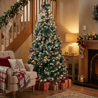 Artificial Christmas tree with lit branches, red baubles, on metal stand.