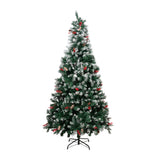 Artificial Christmas tree with lit branches and red ornaments on metal stand base.