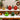 Christmas ornaments on snowy wooden display: gold, red, green baubles and teardrops