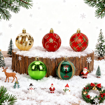 Christmas ornaments on snowy log: gold, red, green baubles and a teardrop