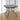 Metal square outdoor dining table with black tabletop, curved legs, and lower shelf