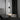 Black linear LED wall sconce with round backplate and vertical bar, white glow