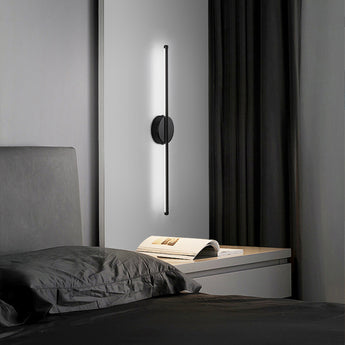 Black linear LED wall sconce with round backplate and vertical bar, white glow
