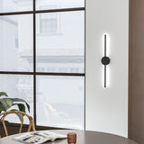Black linear LED wall sconce with round backplate and vertical light bar, white glow