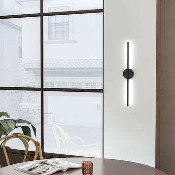 Black linear LED wall sconce with round backplate and vertical light bar, white glow