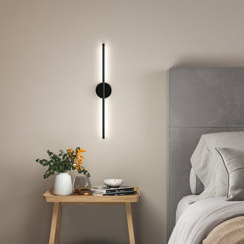 Black linear LED wall sconce with round backplate and vertical light bar, warm glow