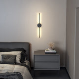 Black linear LED wall sconce with round backplate and vertical light bar, warm glow