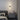 Black linear LED wall sconce with round backplate and vertical light bar, warm glow