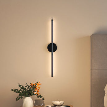 Black linear LED wall sconce with round backplate and vertical light bar, warm glow