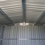 Interior view of metal shed ceiling with beams and ventilation opening, corrugated walls