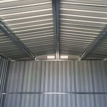 Interior view of metal shed ceiling with beams and ventilation opening, corrugated walls