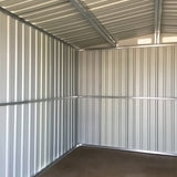 Empty interior of green metal storage shed with corrugated walls and ceiling beams