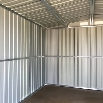 Empty interior of green metal storage shed with corrugated walls and ceiling beams
