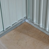 Corner inside metal storage shed with smooth floor base and corrugated green walls