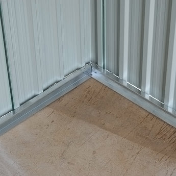 Corner inside metal storage shed with smooth floor base and corrugated green walls