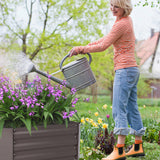 Raised garden bed planter box with gray metal slats beside blooming purple flowers
