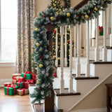 Artificial LED Christmas garland with gold baubles and warm white lights on staircase