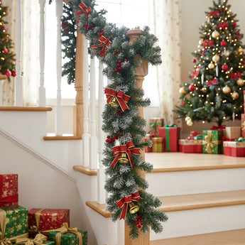 Artificial LED Christmas garland with red bows and warm white lights on stair post