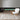 Black electric fireplace with green flame effect behind a glass viewing window.
