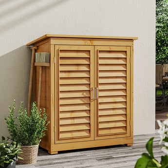 Outdoor wooden storage shed with double louvered doors closed and broom stored nearby