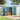 Green and charcoal metal garden storage shed with closed doors and louvered side panels.