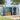 Green and charcoal metal garden storage shed with side door open, showing storage interior.