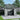 Outdoor metal garbage storage shed with hinged lid open and double doors, holding a bicycle