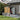 Tawny outdoor storage shed with double doors, open side bay and gray metal paneling
