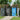 Outdoor metal garbage can storage shed, double doors open with gray and blue bins