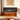Electric fireplace insert with black frame and orange flame display on wooden console