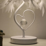 Heart-shaped metal stand with clear crystal pendant under white feather lampshade