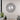 Decorative wall clock with round face, black numbers, silver crystal accents, and feather-like metal hands.