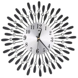 Close view of a metal sunburst wall clock with round face, black numerals, and crystal bead drops.