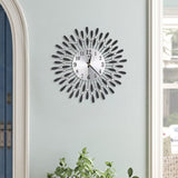 Sunburst metal wall clock with round dial, black numbers, and sparkling crystal drop accents.