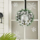 Artificial Christmas wreath with silver ribbon, pine leaves, and white floral ornaments