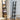 Black ladder-style wall shelves with four open tiers, clock and small home decor
