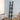 Black ladder-style wall shelf with four tiers, vase and small plant decor