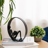 Desktop metal statue of a man reading inside a circular ornament figurine