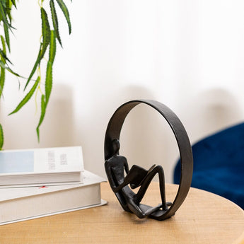 Man reading desk statue with dark circular frame ornament, metal figurine