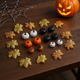 Assorted Halloween pumpkin and maple leaf ornaments on tabletop, orange white black